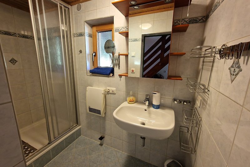 Badezimmer mit Spiegel, Wasserhahn, Waschbecken und Fliesenboden.