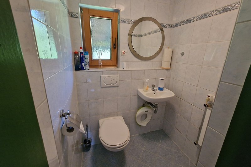 Badezimmer mit Fliesen, Spiegel und Waschbecken.