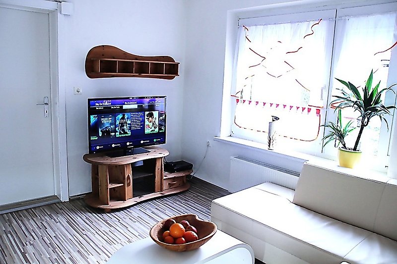 Gemütliches Wohnzimmer mit stilvollem Interieur, bequemer Couch und Fernseher.