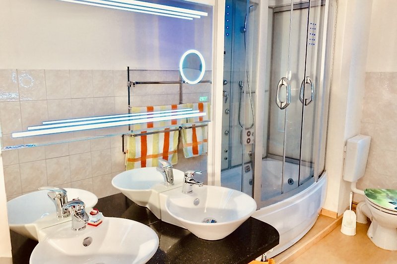 Gemütliches Badezimmer mit Doppelwaschbecken und  Spiegel.