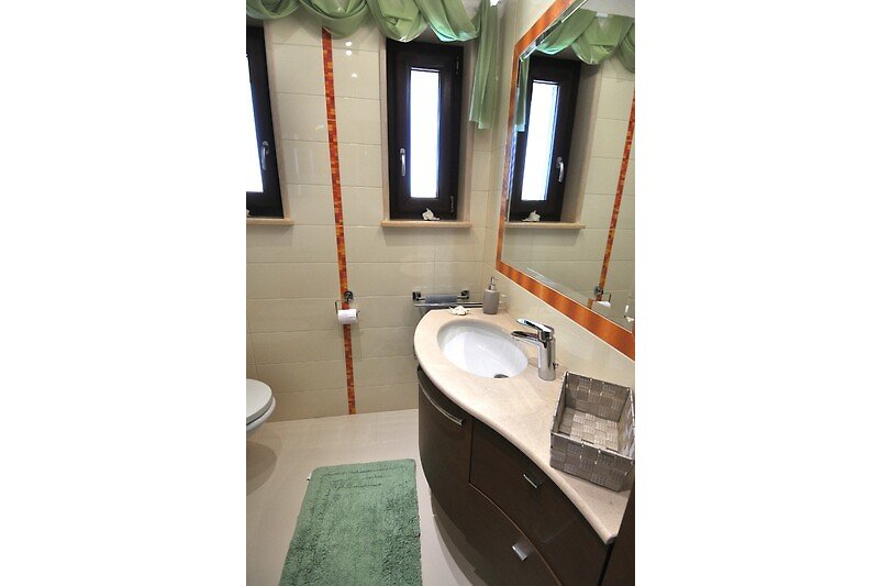 Modernes Badezimmer mit elegantem Spiegel und Metallarmaturen.