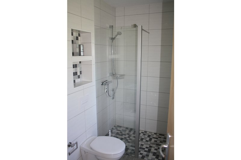 Modernes Badezimmer mit Fliesenboden, Toilette und Duschkabine
