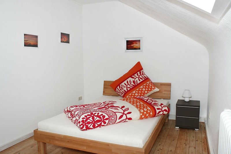 Gemütliches Schlafzimmer mit Holzbett und orangefarbenem Lampenschirm.