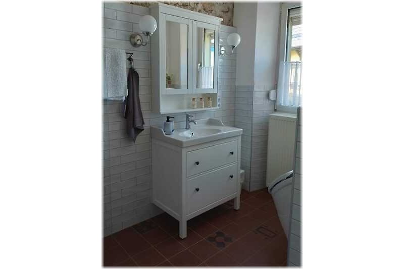 Moderne Badezimmerausstattung mit Spiegel, Waschbecken, Waschmaschine, Dusche und WC im EG