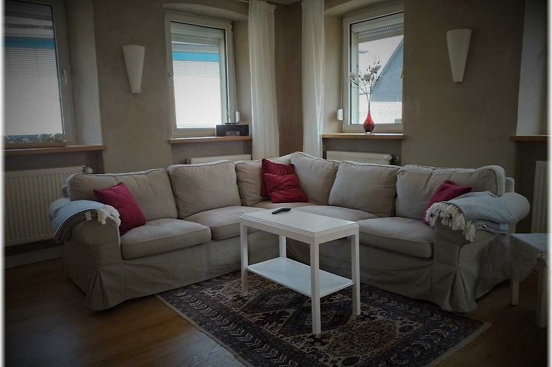Gemütliches Wohnzimmer mit Holzboden und gemütlicher Couch.