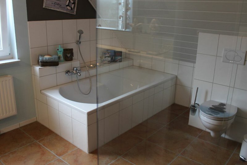 Großes Badezimmer mit Badewanne, Dusche, Spiegel und Fußbodenheizung.