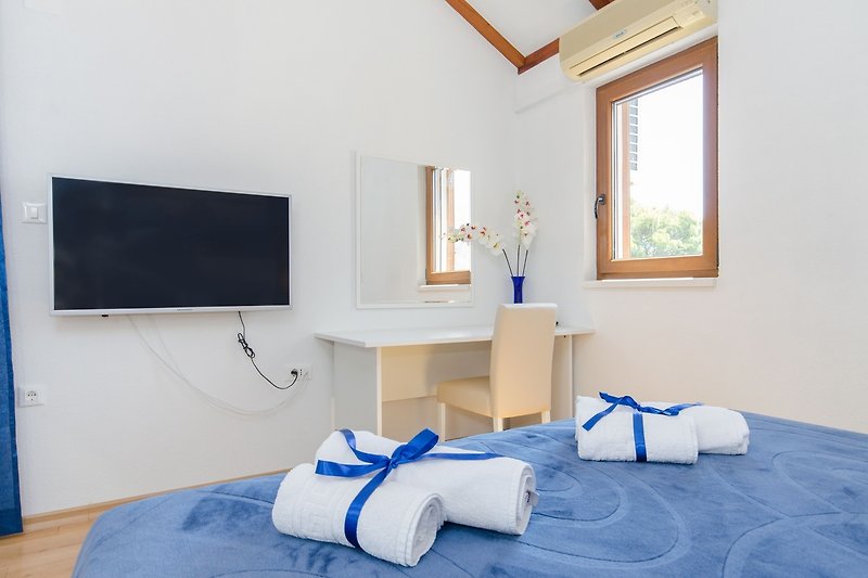 Einladendes Schlafzimmer mit blauem Bett und Holzmöbeln.