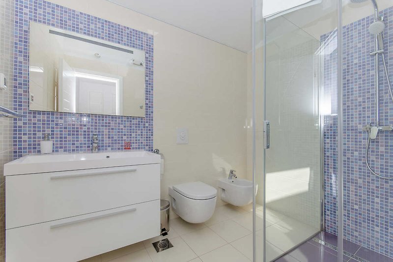 Badezimmer mit blau  Akzenten, Spiegel und Dusche.