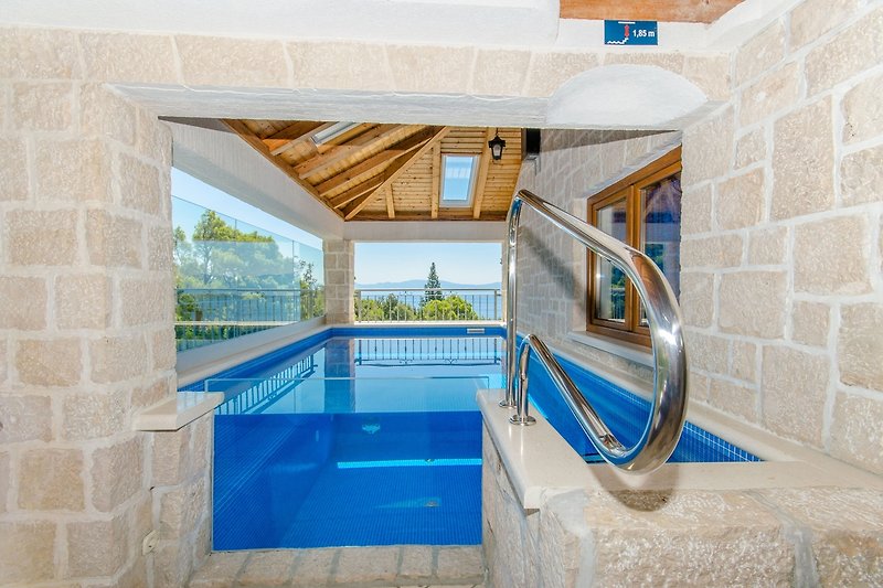 Schwimmbad mit Blick auf das Meer, moderne Architektur und stilvolle Inneneinrichtung.