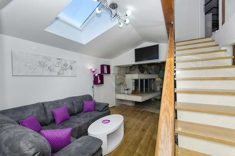 Gemütliches Wohnzimmer mit lila Couch und stilvoller Beleuchtung.