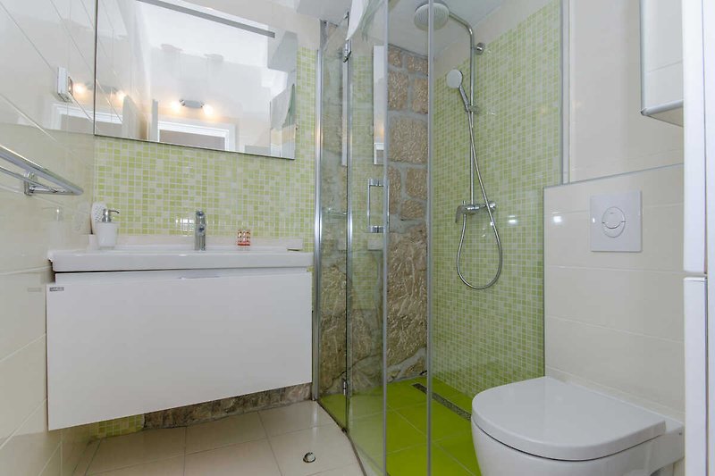 Ein angenehmes grünes Badezimmer aus Stein mit Duschkabine.