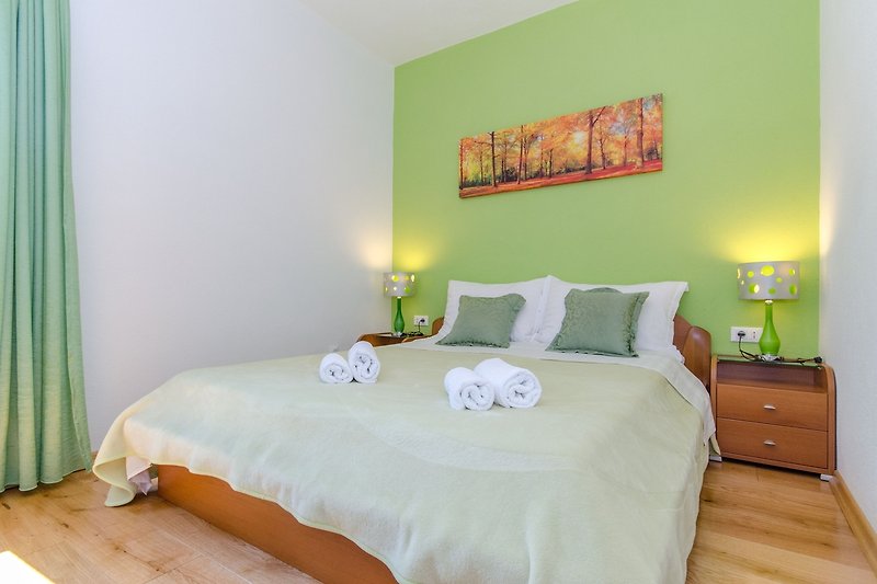 Gemütliches Schlafzimmer mit Holzmöbeln und grünen Akzenten.
