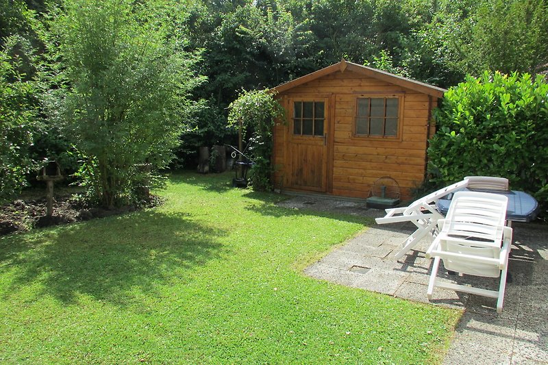 Ein rustikales Holzhaus mit grüner Landschaft und Gartenmöbeln.