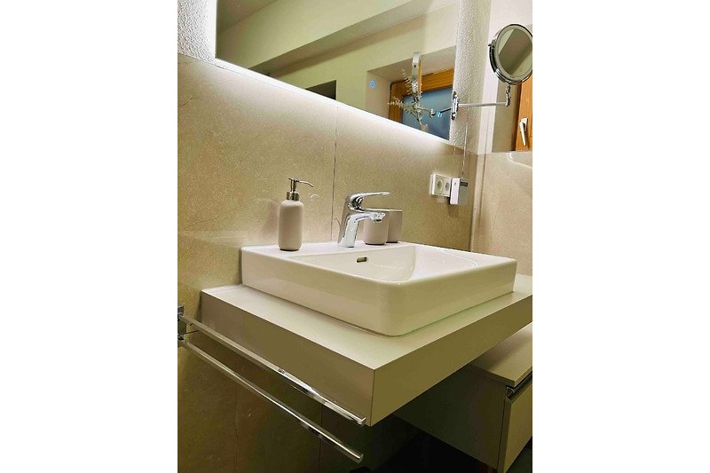 Ein modernes Badezimmer mit Spiegel, Waschbecken und Holzdetails.