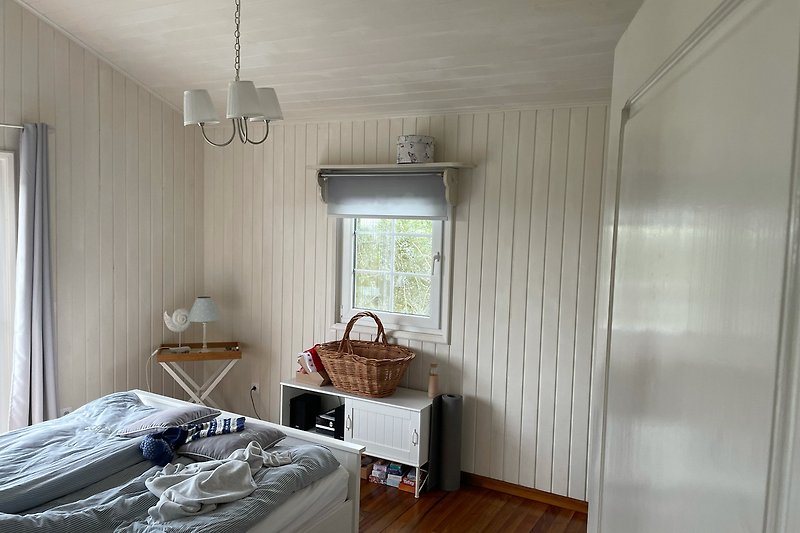 Gemütliches Schlafzimmer mit stilvoller Einrichtung, hell und Meerblick vom Bett aus.
