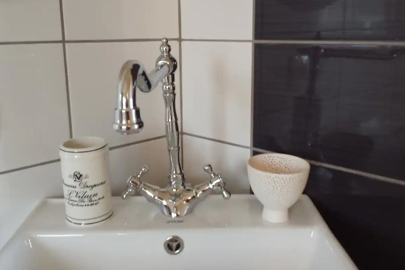 Geräumiges Badezimmer mit stilvollen Fliesen und  modernem Waschbecken.