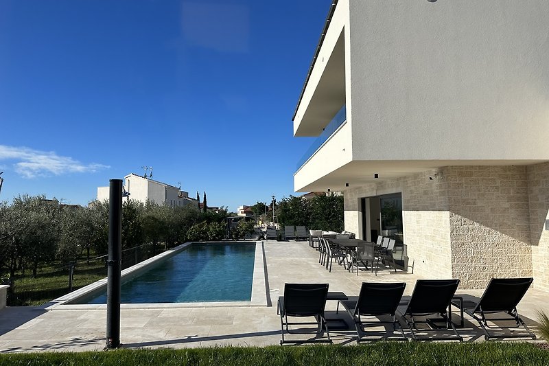 Schöner Pool mit modernem Design und bequemen Außenmöbeln .