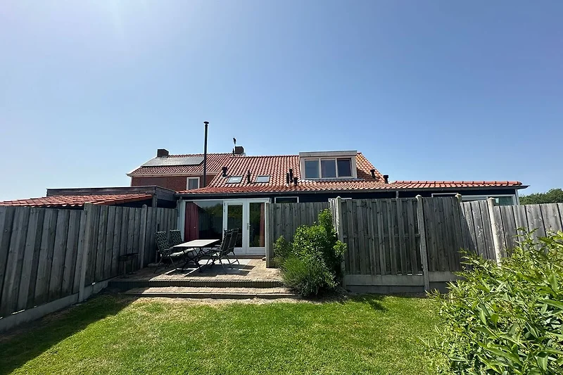Schönes Haus mit Garten, Terrasse und Zaun.
