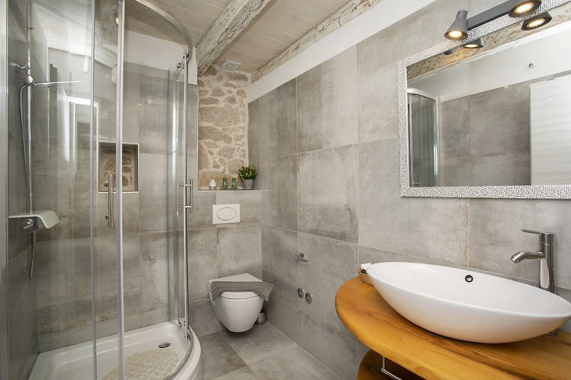 Elegantna kupaonica s modernim umivaonikom i staklenim vratima.