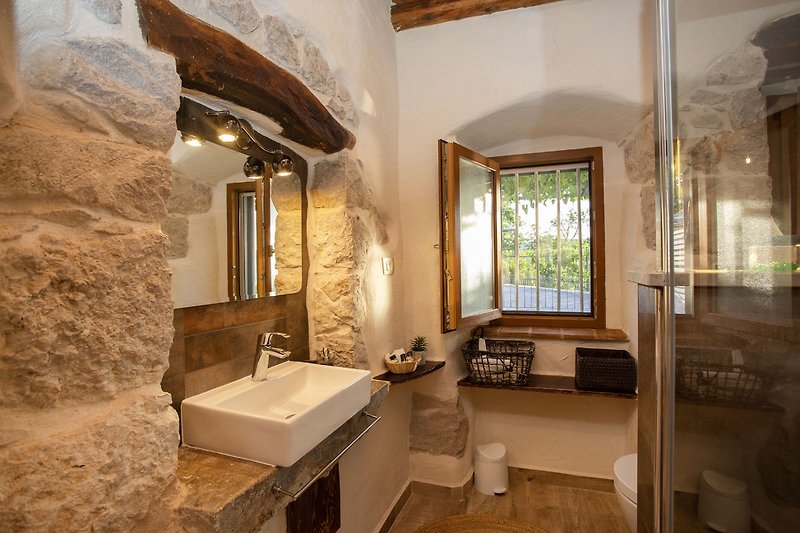Elegantna kupaonica s umivaonikom, ogledalom i modernim osvjetljenjem.