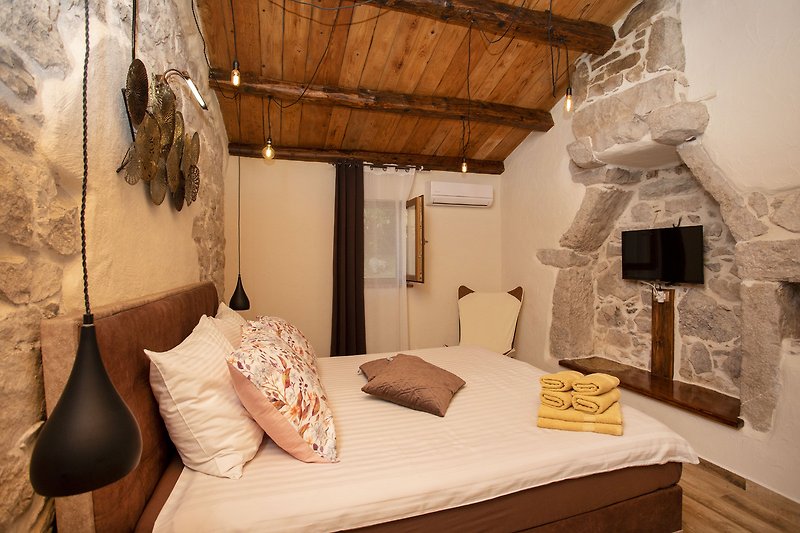Udobna spavaća soba s drvenim krevetom i udobnom posteljinom.