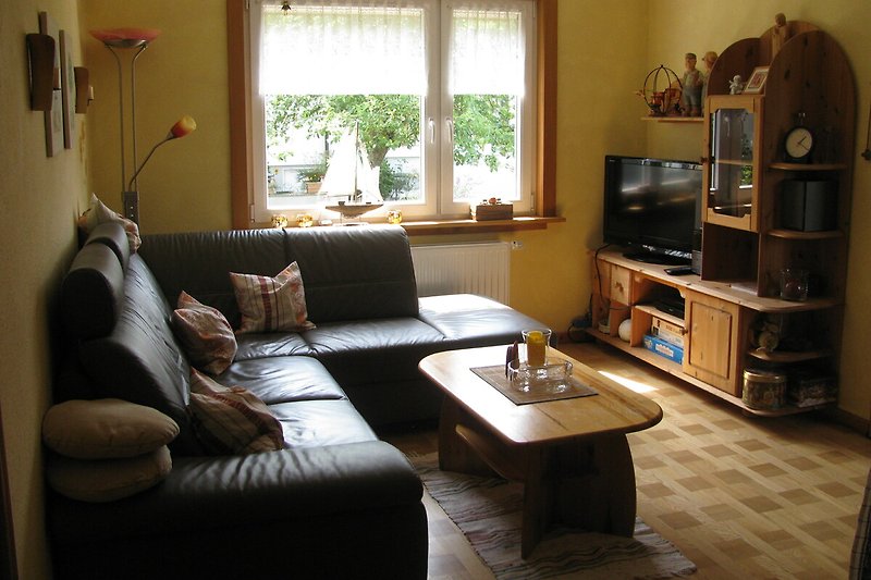 Wohnzimmer mit Holzmöbeln, Fernseher, Stereoanlage und bequemer Couch.