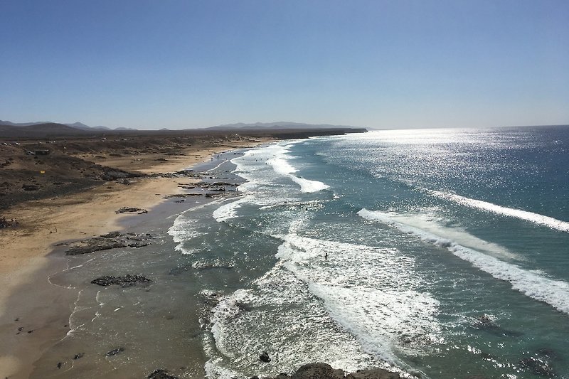 Una vista mozzafiato sull'oceano con spiaggia di sabbia bianca e onde che si infrangono sulla costa.