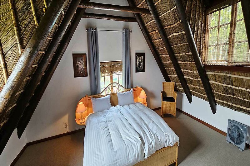 Gezellige tweepersoons slaapkamer met houten meubels en sfeervolle verlichting.