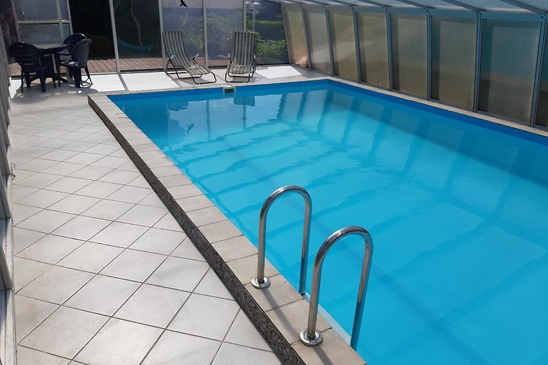 Moderne Ferienwohnung mit Pool, Sonnenliegen und Blick aufs Wasser.
