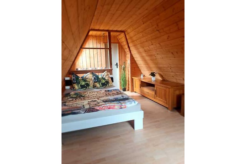 Gemütliches Schlafzimmer mit Holzmöbeln, bequemem Bett und Fernseher