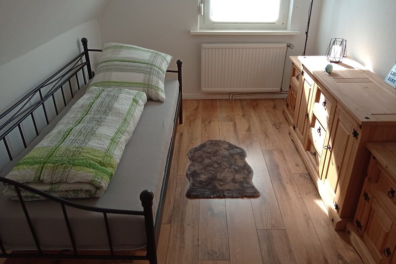 Gemütliches Schlafzimmer mit Holzbett, Bettwäsche und Kunst an der Wand. Holz, Komfort, Fenster.