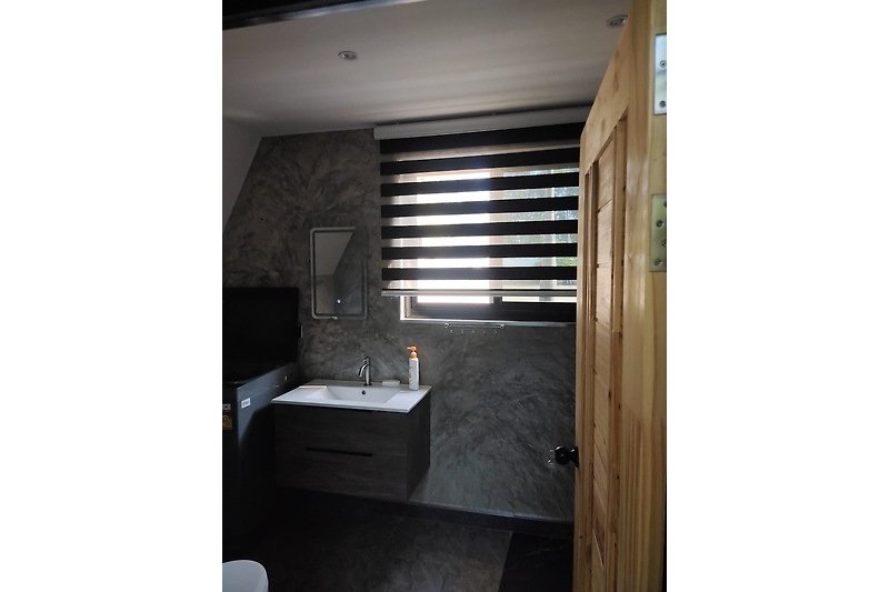 Schönes Badezimmer mit Holzboden, Waschbecken und Fenster.