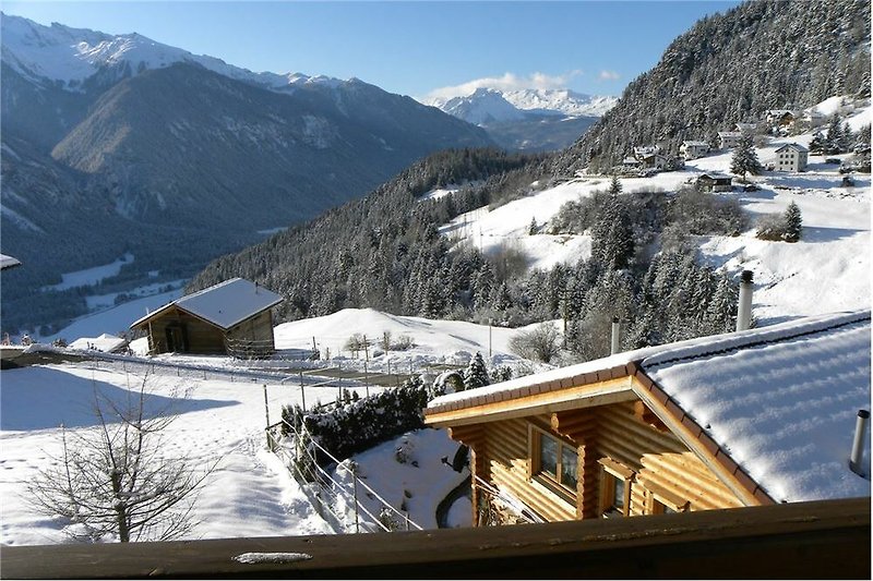 Gemütliches Ferienhaus mit verschneiter Berglandschaft und malerischem Balkon-Ausblick.
