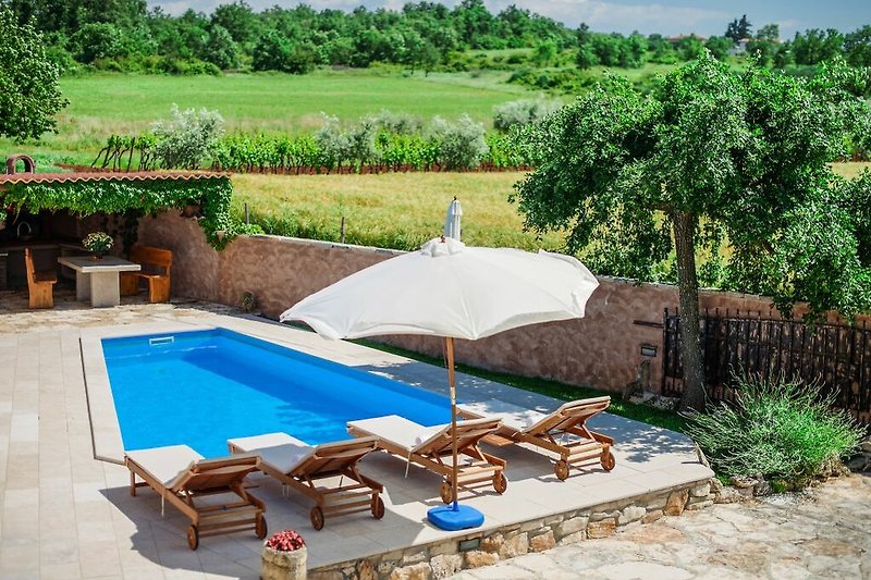 Schöne Ferienvilla mit Pool und Außenmöbeln. Entspannen Sie im Schatten unter dem Sonnenschirm.