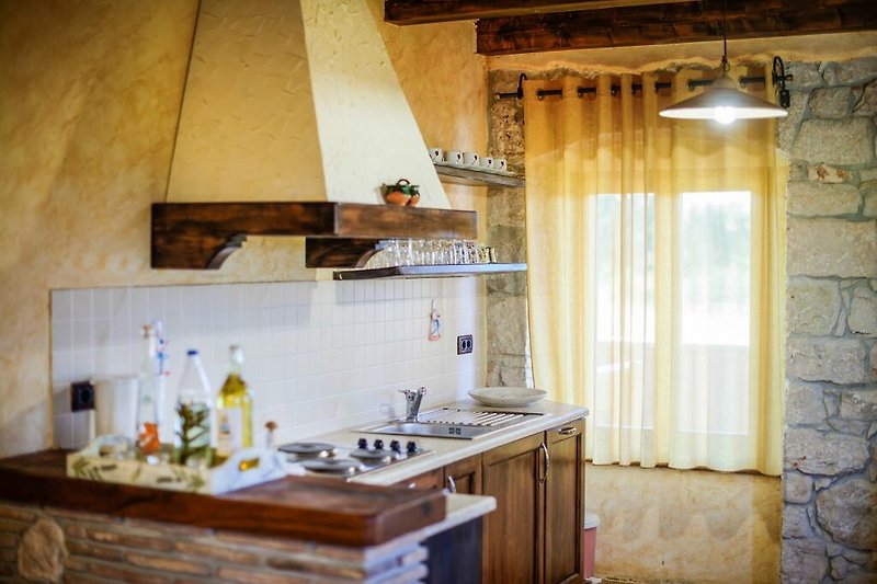 Schöne Küche mit Holzboden, Fenster und Geräten.