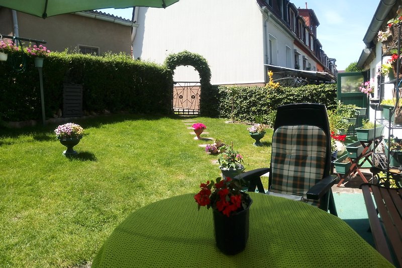 Garten mit Tisch, Stühlen und Blumen.
