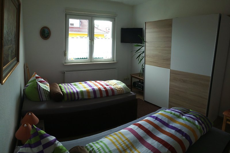 komfortables Schlafzimmer mit 2 Liegen Schiebetürenschrank und TV