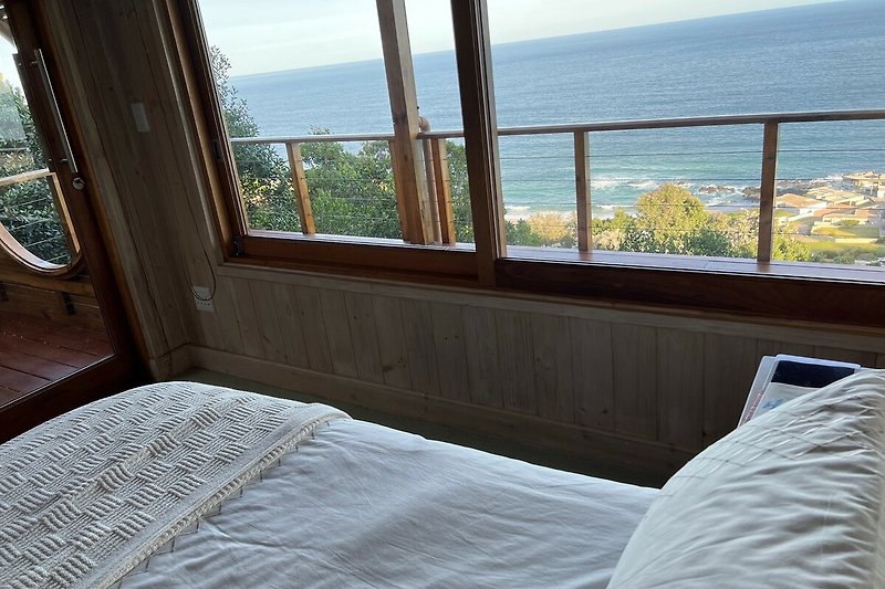 A comfortable bedroom with a view of the azure lake and lush greenery.