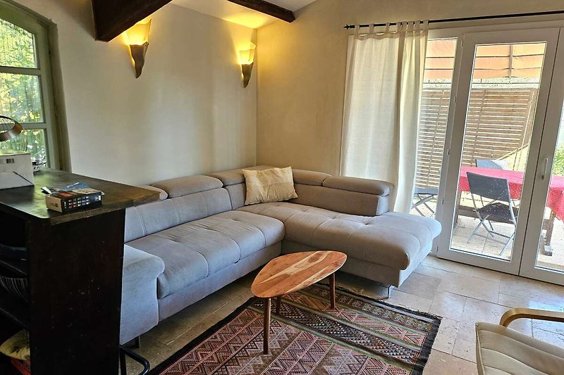 Wohnzimmer mit bequemer Couch, Holzmöbeln und bodentiefen Fenstern/Durchgang zur Terrasse