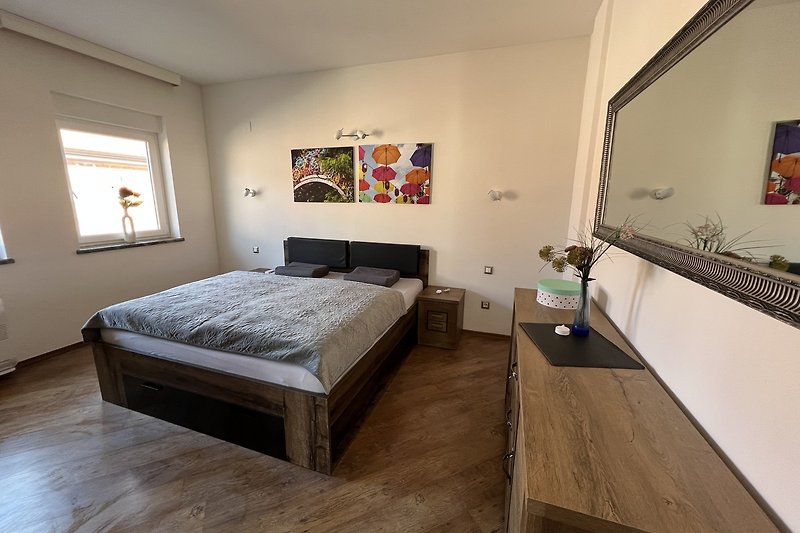 Ein stilvoll eingerichtetes Schlafzimmer mit Holzboden und gemütlichem Doppelbett.