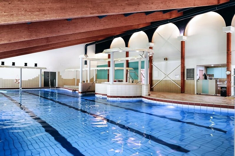 Schwimmbecken mit blauem Wasser und modernem Gebäude.