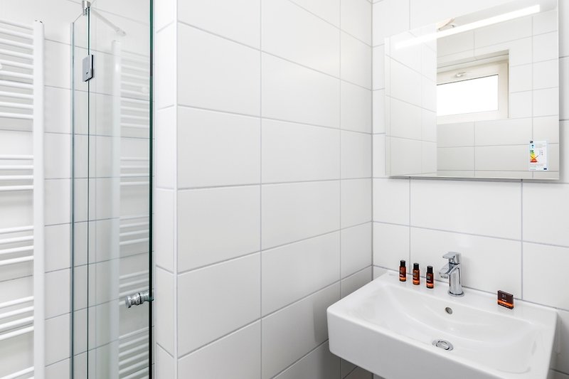 Moderne Badezimmerausstattung mit Spiegel, Wasserhahn und Waschbecken.