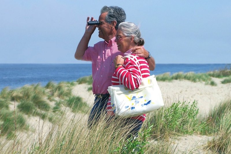 Glückliche Menschen genießen den Strand mit Kamera und Gepäck.