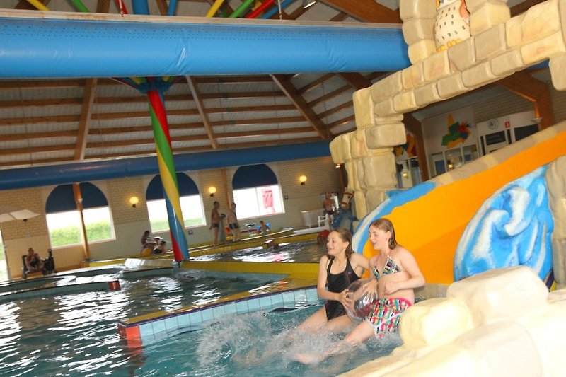 Schwimmspaß im gelben Freizeitpark mit Wasserrutsche und aufblasbaren Spielen.