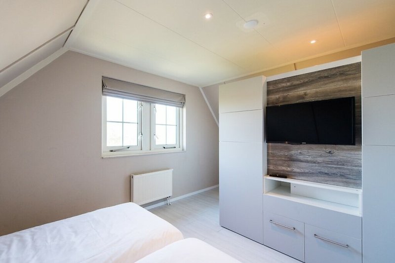 Gemütliches Schlafzimmer mit Holzmöbeln und stilvoller Beleuchtung.