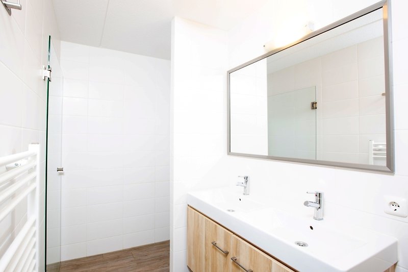 Schönes Badezimmer mit Spiegel, Waschtisch und Holzschränken.
