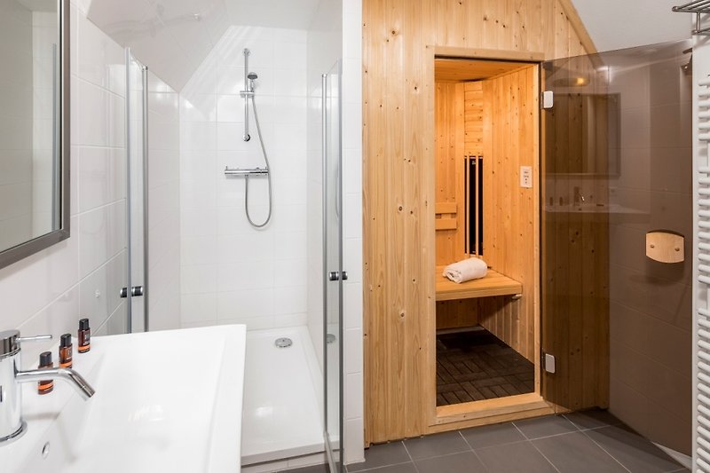 Schönes Badezimmer mit Holzboden, Dusche und stilvoller Armatur.