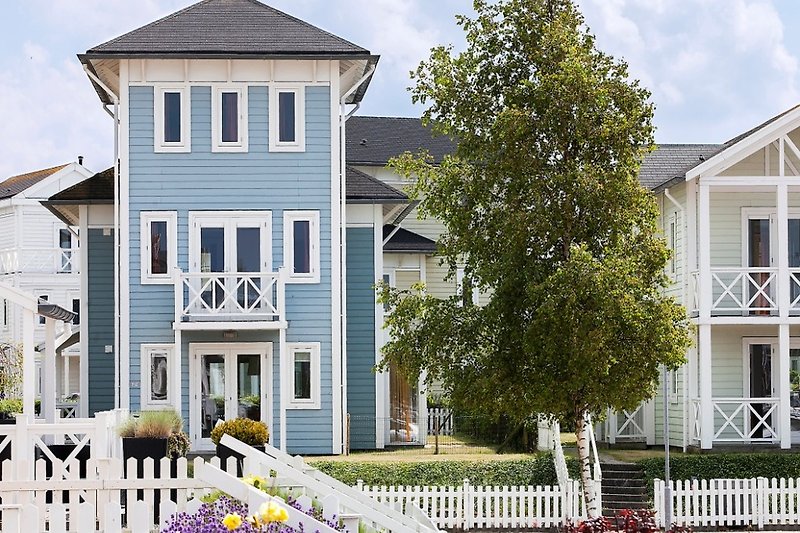 Schönes Haus mit blauem Himmel, Fenster und weißem Zaun.