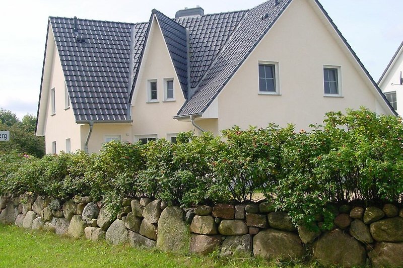 Schönes Haus mit grünem Garten, großen Fenstern und schöner Fassade.