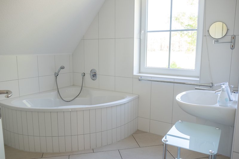 Schönes Badezimmer mit Badewanne, Waschbecken und Fenster.